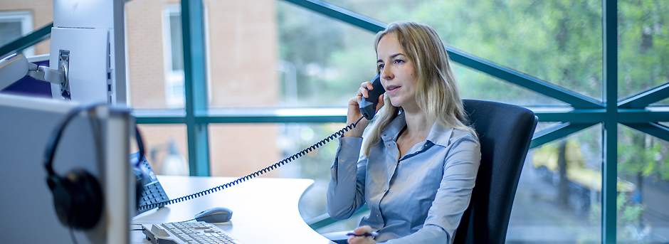 Vrouw telefoneert bij computerscherm op kantoor