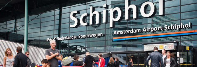 Reizigers staan klaar met hun koffers voor de deur van Schiphol